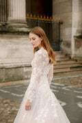 Woman wearing Monique Lhuillier Fall 2023 Bliss long sleeve v-neck white embroidered tulle a-line BL23203 gown