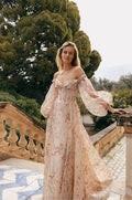 Woman wearing blush and multicolored floral printed off-the-shoulder Monique Lhuillier Spring 2023 Bellini a-line gown with billowed sleeve