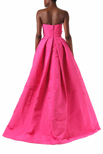 Monique Lhuillier Fall 2024 strapless, a-line ballgown in fuchsia floral embossed faille with draped asymmetrical bodice and full pleated skirt - back.