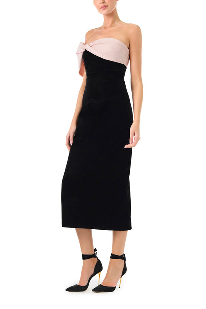 Monique Lhuillier Fall 2024 black velvet off the shoulder sheath dress with pale blush draped, asymmetric twist detail at neckline - right side.