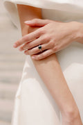 Woman wearing Monique Lhuillier Fall 2023 Bliss BL23204 gown wearing a black and white diamond emerald cut ring