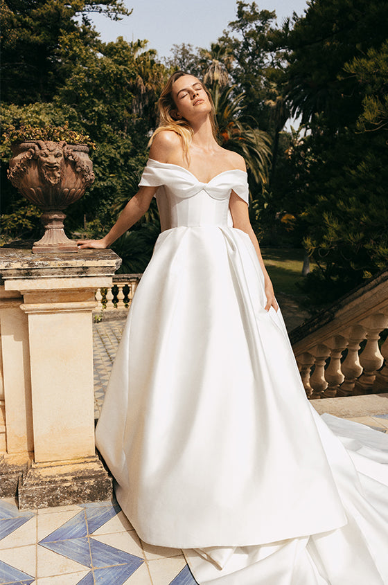 Woman wearing Monique Lhuillier Spring 2023 white mikado corseted off-the-shoulder Luisa ballgown