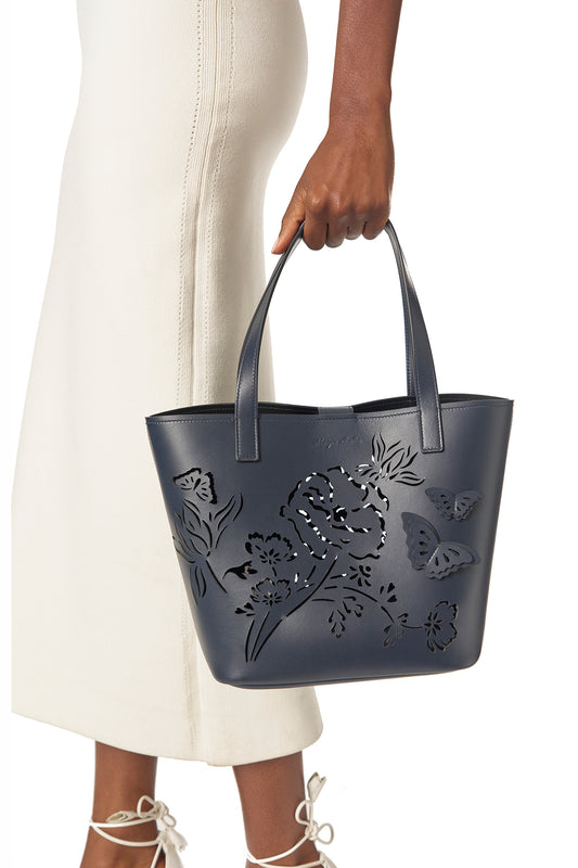 Leather top handle tote bag with laser cut florals, three-dimensional leather butterflies and small zip pouch in Navy- modeled