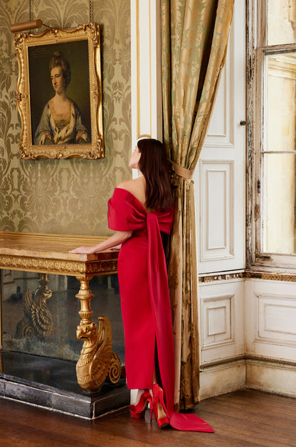 Monique Lhuillier Fall 2024 off-the-shoulder tea length column dress with draped neckline and bow-train in pomegranate silk faille - lookbook.