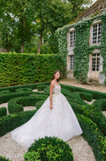 Woman wearing Monique Lhuillier Fall 2023 white spaghetti strap Esprit ballgown with green and lavender floral embroidery