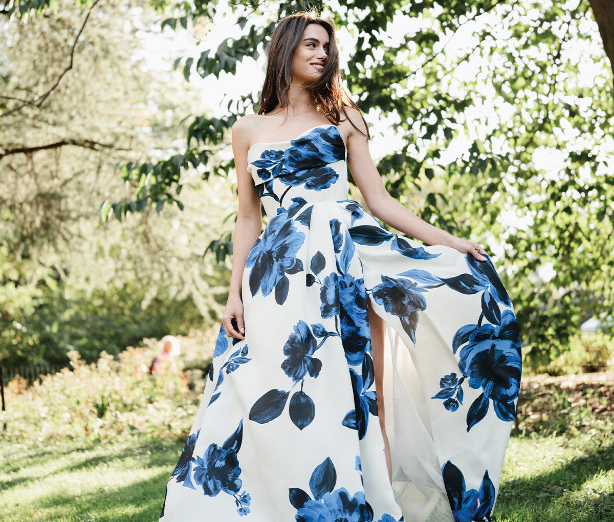 Monique Lhuillier Spring 2025 blue and white draped bodice ballgown on model by tree 