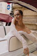 Woman wearing Monique Lhuillier Spring 2023 Bliss white lace sweetheart fitted trumpet BL23101 gown with matching lace opera-length gloves