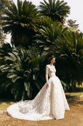 Woman wearing ivory lace Monique Lhuillier Spring 2023 Angelina ballgown with high-neck long sleeve lace Angelina jacket