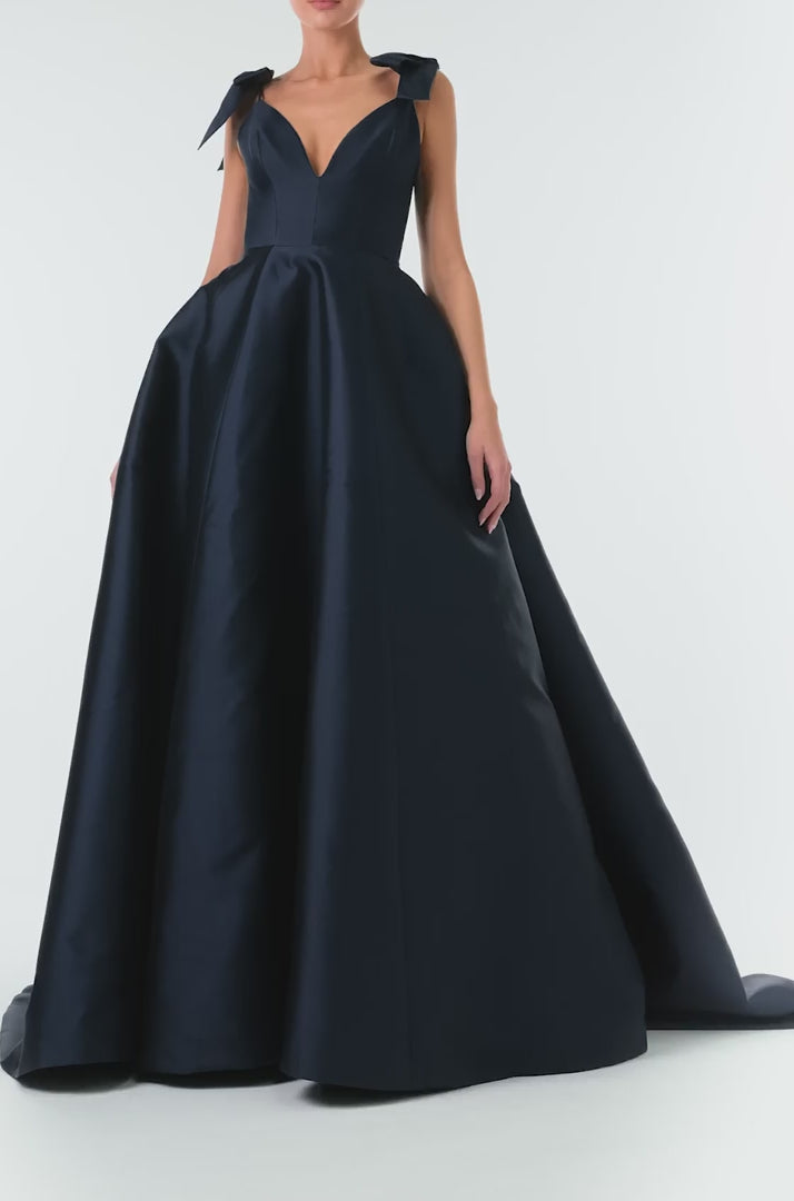 Monique Lhuillier Fall 2024 deep V-neck ball gown in navy mikado with full skirt and bow detail at shoulders - video.