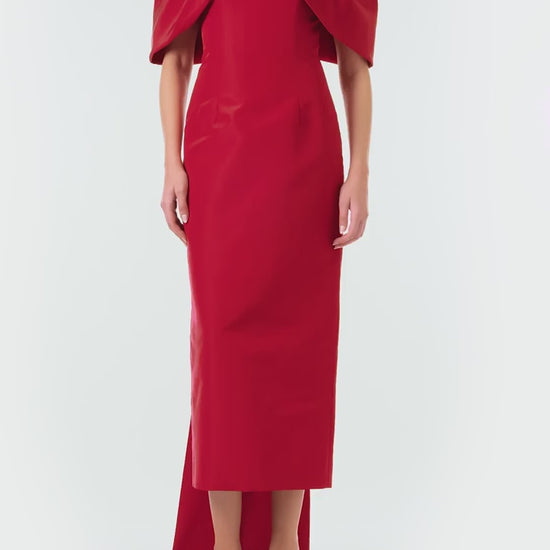 Monique Lhuillier Fall 2024 off-the-shoulder tea length column dress with draped neckline and bow-train in pomegranate silk faille - video.