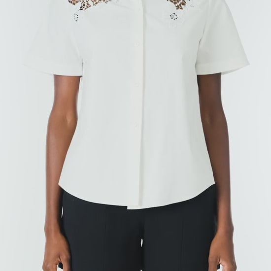 Monique Lhuillier Spring 2025 Short sleeve, button-down shirt with collar in white cotton poplin and lace applique details at shoulder - video.