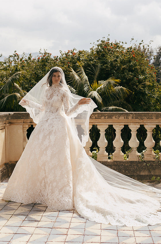 Woman wearing ivory lace Monique Lhuillier Spring 2023 Angelina ballgown with lace Angelina jacket and lace-trimmed Angelina veil